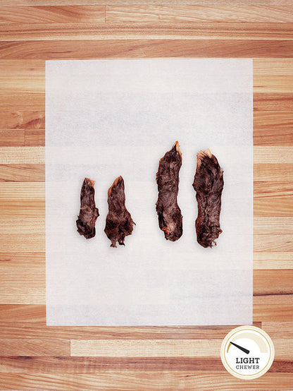 four brown small and large rabbit feet on a butcher block countertop