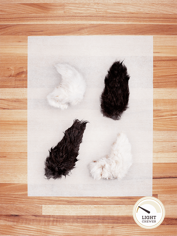 four black and white rabbit tails with hair on butcher block countertop