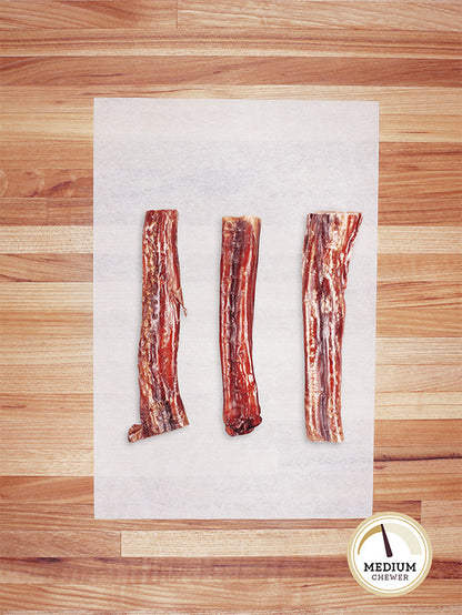 three short beef bully sticks on a butcher block countertop