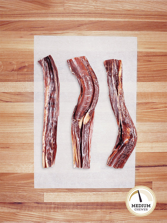 three beef bully sticks on a butcher block countertop